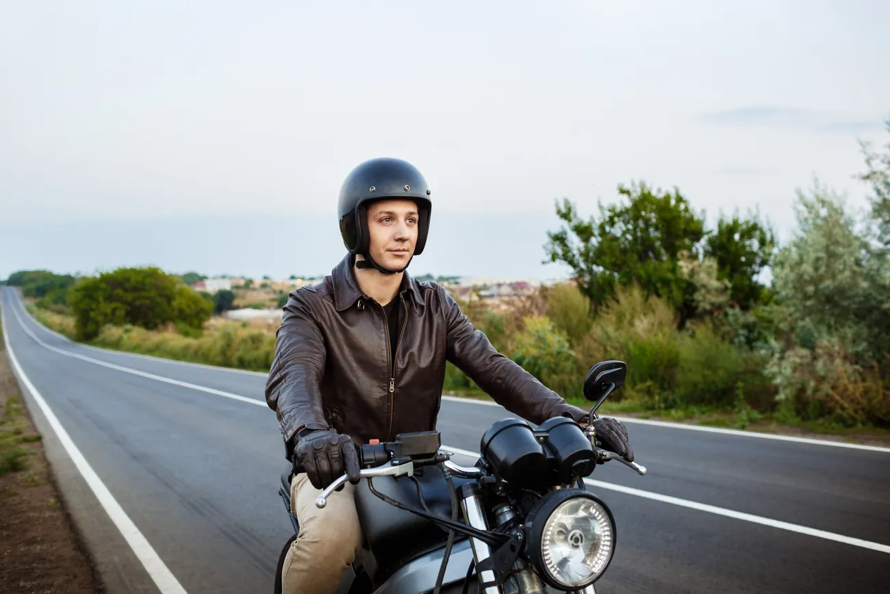 Motociclista de capacete parado em uma estrada