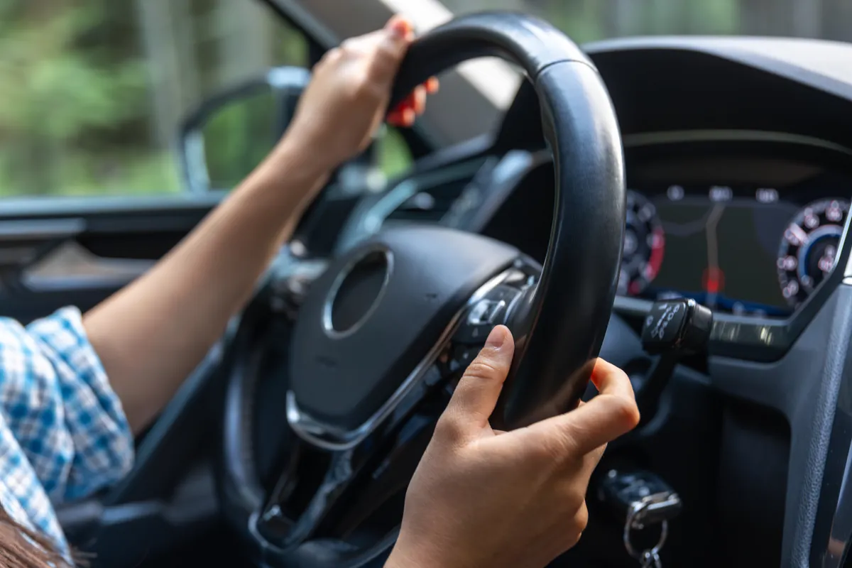 Mãos ao volante dirigindo um carro na estrada