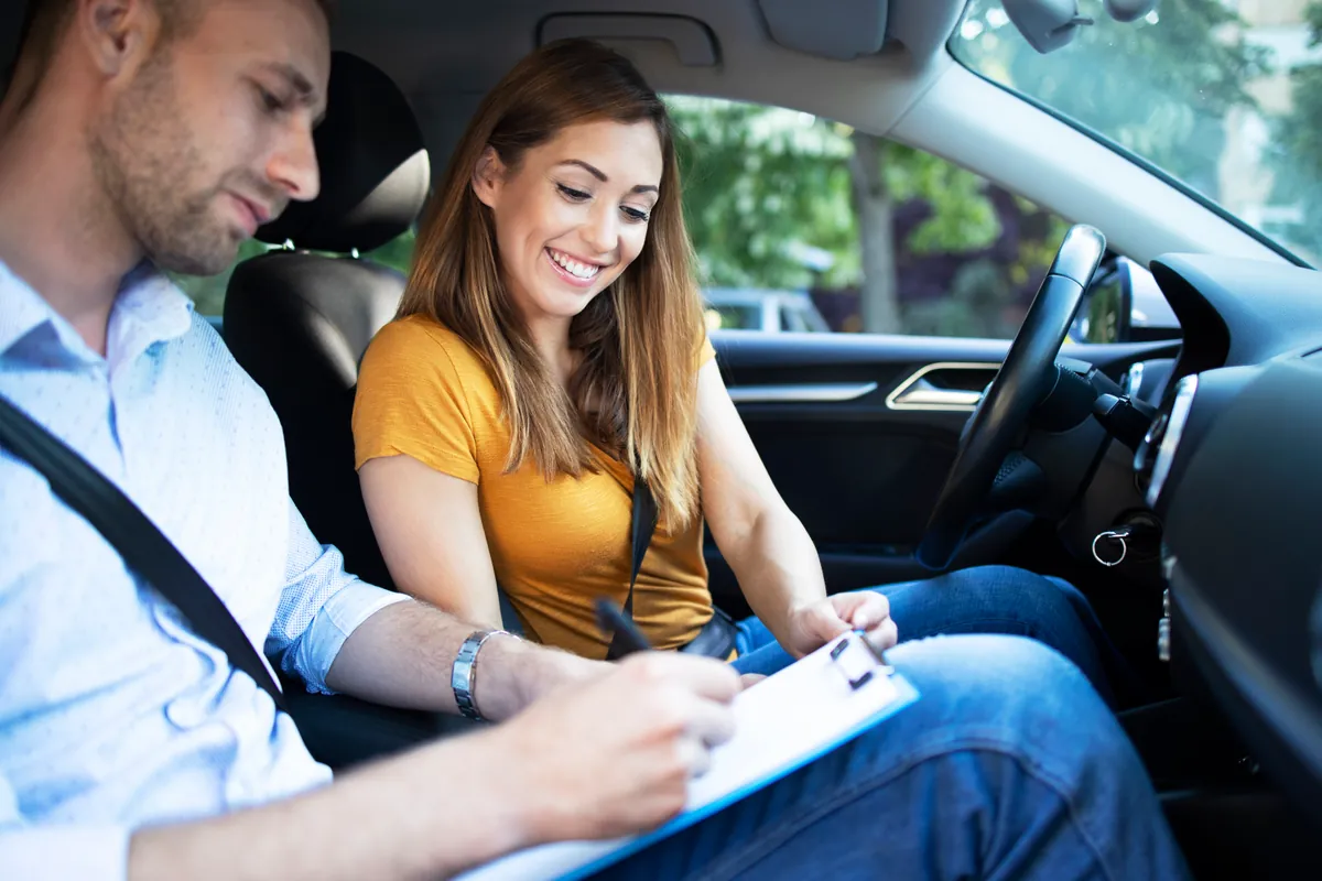 Instrutor explicando o conteúdo teórico e a legislação ao aluno dentro do carro